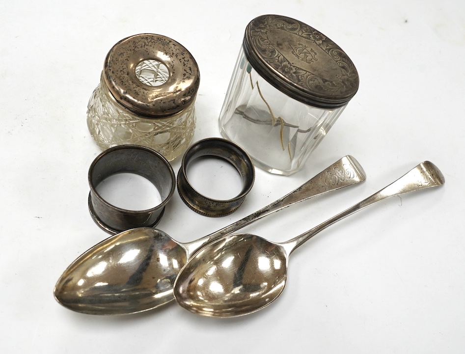 Two George III provincial silver Exeter table spoons, 22cm, two silver napkin rings and two silver mounted glass toilet jars. Condition - poor to fair